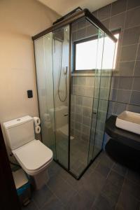 a bathroom with a toilet and a glass shower at Villa Real Chalés in Viçosa do Ceará +81 photos