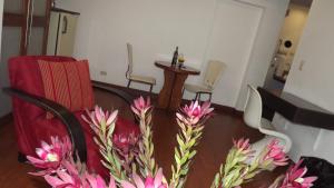 a room with a chair and a table with pink flowers at Hotel Retiro 84 in Bogotá