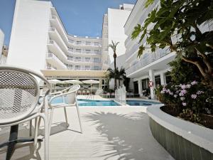 a patio with chairs and a pool in a building at Hotel Miami Calella in Calella