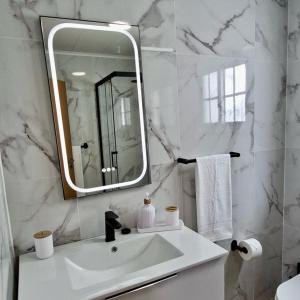a white bathroom with a sink and a mirror at Vila de Baixo in Lajes das Flores +30 photos