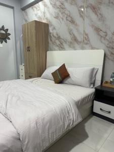 a bedroom with a white bed and a marble wall at The friendly stay in Male City