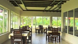 a dining room with tables and chairs and windows at The Infinity Pench Resort in Khawāsa