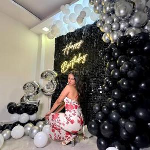 a woman in a dress in front of a wall of balloons at Brown oak farms in Sohna