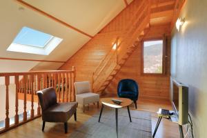 a living room with a staircase with chairs and a television at Chalet la roche du rain in Gérardmer