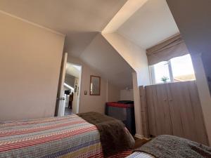 an attic bedroom with two beds and a window at Decher Apartment - Puerto Varas in Puerto Varas