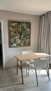 a table and a chair in a room with a painting at 29 Village Place in Gaborone