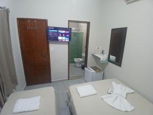 a bathroom with two beds and a toilet and a television at Pousada Milagres de Maria in Aparecida