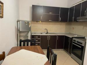 a kitchen with brown cabinets and a table and a sink at Endi Apartments 2 in Tirana