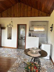 a living room with a table and a kitchen at Chalé Aconchego da Paz - Chalé 2 in Lavras Novas