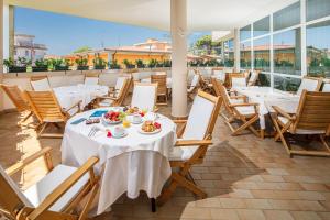 a restaurant with tables and chairs with food on it at Hotel Jasminum in Bibione