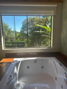 a bath tub in a room with a window at Chalé Aconchego da Paz - Chalé 1 in Lavras Novas +14 photos