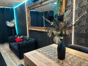 a living room with a couch and a vase with a plant at Chambre de charme, sauna, jacuzzi,billard VIP, clim in Verviers +47 photos