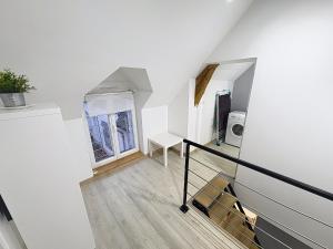 a room with white walls and a staircase with a window at Le Petit Curie in Gien