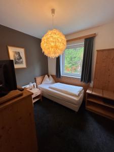 a bedroom with a bed and a window and a chandelier at WILDAUERS Ansitz Haidenhof STAY & SLEEP in Lienz