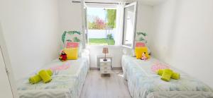 two twin beds in a room with two windows at Fleur De Cerisier Vendée in Challans