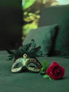 a masquerade mask and a rose on a bed at Chambre de charme, sauna, jacuzzi,billard VIP, clim in Verviers