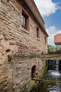 an old stone building with a waterfall next to it at Maison d'hôtes complète La Paulusmühle in Soucht +133 photos