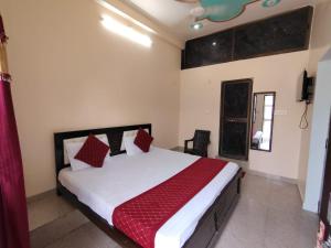 a bedroom with a large bed with red pillows at Shri Sitaram Guest House in Ayodhya