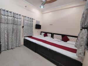 a bedroom with a large bed with red pillows at Shri Sitaram Guest House in Ayodhya