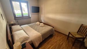 a bedroom with a bed and a chair and a window at Saroio B in Auronzo di Cadore