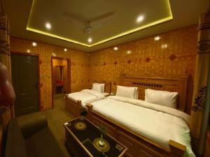 a bedroom with two beds and a table in it at Hotel Blangsa Indus View in Skardu