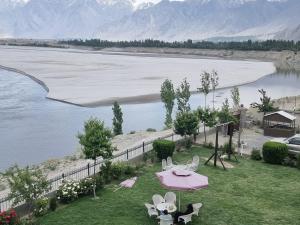 a view of a lake with a pink table and chairs at Hotel Blangsa Indus View in Skardu