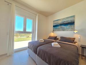 two beds in a room with a window at Villas By George in Afiartis