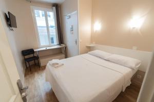 Cette petite chambre dispose d'un lit blanc et d'une fenêtre. dans l'établissement Hôtel De La Gare, à Villeneuve-Saint-Georges