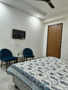 a bedroom with a bed and two chairs and a television at Cozy Cove in Jaipur