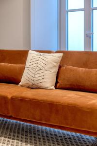 a brown couch with a white pillow on it at Glasgow Industrial 2BR apartment in Caparica