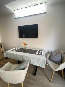 a living room with a table and chairs and a tv at Jena Ferienwohnung Campusblick in Jena