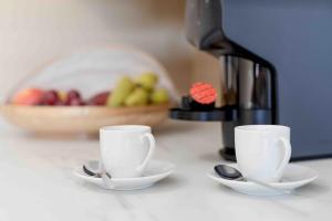two cups and spoons on a counter with a coffee maker at Modern 2 bedroom apt 20 min from city center in Amadora +43 photos
