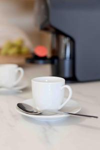 two white cups and saucers sitting on a table at Modern 2 bedroom apt 20 min from city center in Amadora