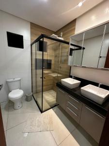 a bathroom with two sinks and a shower and a toilet at Sobrado amplo com churrasqueira in Rio Verde