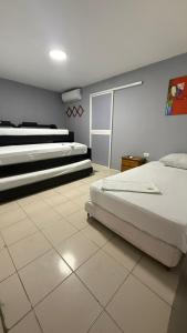 a bedroom with three beds and a tiled floor at Hospedaje El Lorito in Barranquilla