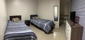 a bedroom with two beds and a dresser and a mirror at Hostal sol del norte in Paipote
