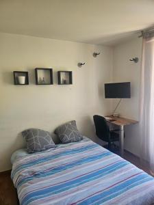 a bedroom with a bed and a desk with a television at Nuits Dijon Chambre in Dijon