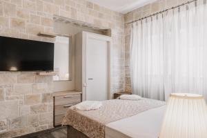 a bedroom with a bed and a tv on a wall at Guince House by All About Paxos in Oziás
