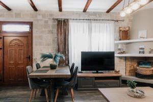 a dining room with a table and a television at Guince House by All About Paxos in Oziás