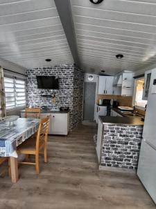a kitchen with a table and a brick wall at Mobilhome rénove climatisé - 10min plage - Mimizan in Mimizan