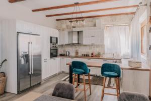 a kitchen with white cabinets and green chairs at Guince House by All About Paxos in Oziás