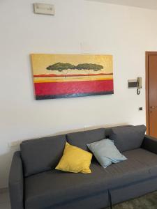 a gray couch with two pillows and a painting on the wall at La casa di Lollo in Piombino