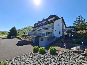 a large white building with a parking lot at Pension Mosella, Gästezimmer in Sankt Aldegund
