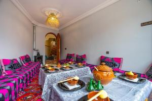 a living room with two tables and pink chairs at Le Reflet D'Imlil in Imlil