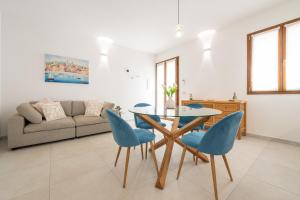 a living room with a glass table and blue chairs at Domus Luna in Teulada