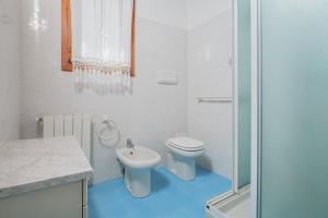 a white bathroom with a toilet and a sink at Villa Montalmutu con vista mare in Nuragheddu +17 photos