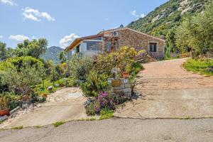 a stone house with a garden in front of it at Villa Montalmutu con vista mare in Nuragheddu