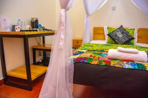 a bedroom with a bed and a table with a bedvisor at Coffee Pot Hotel in Kisoro