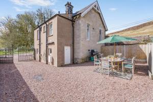 a table and chairs with an umbrella in front of a building at 3 Bed in Langholm oc-c41365 in Langholm