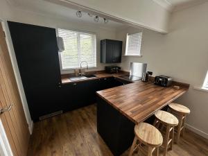 a kitchen with a wooden counter top and stools at Bungalow in Mumbles in The Mumbles